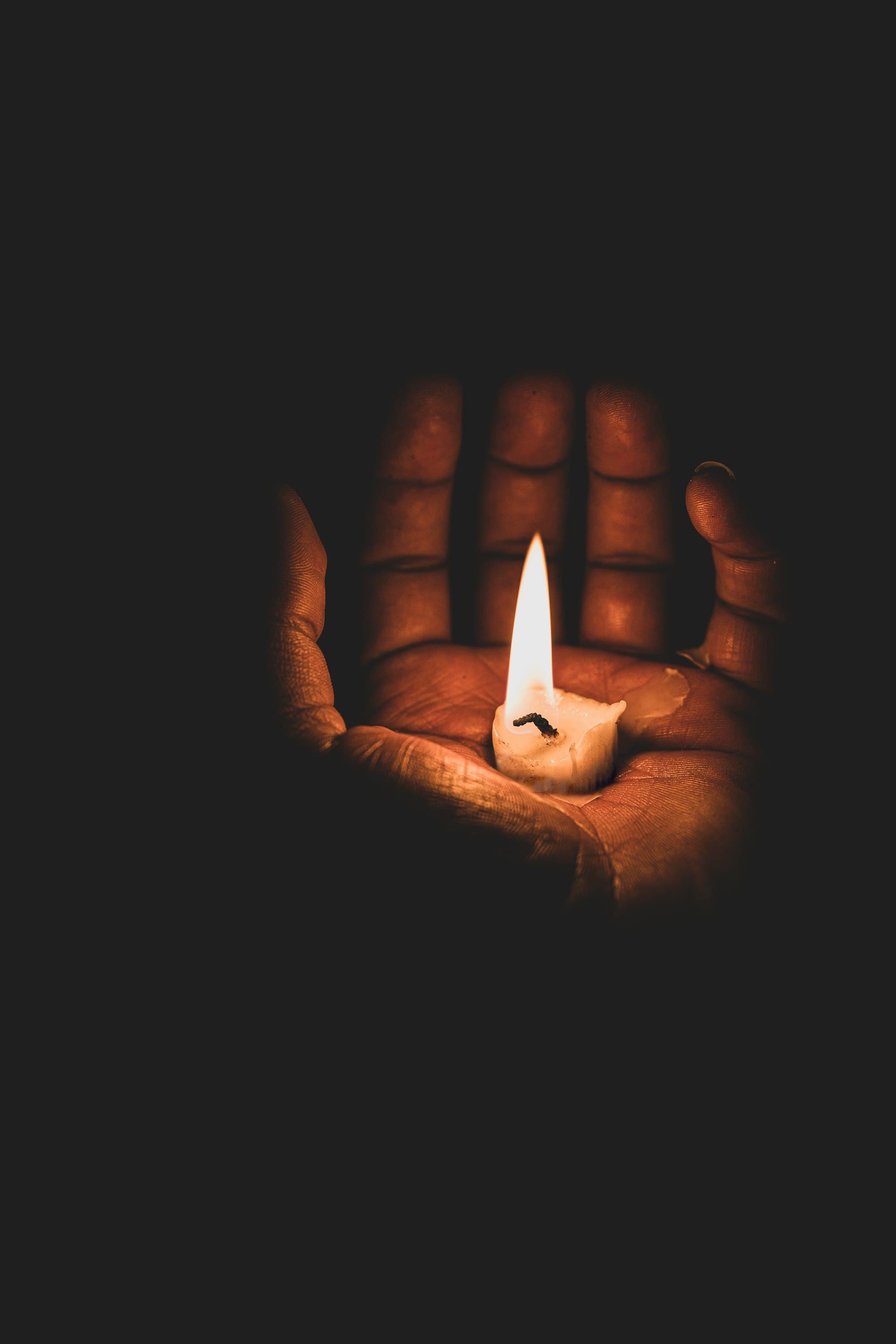 dark room with a lit candle in hand