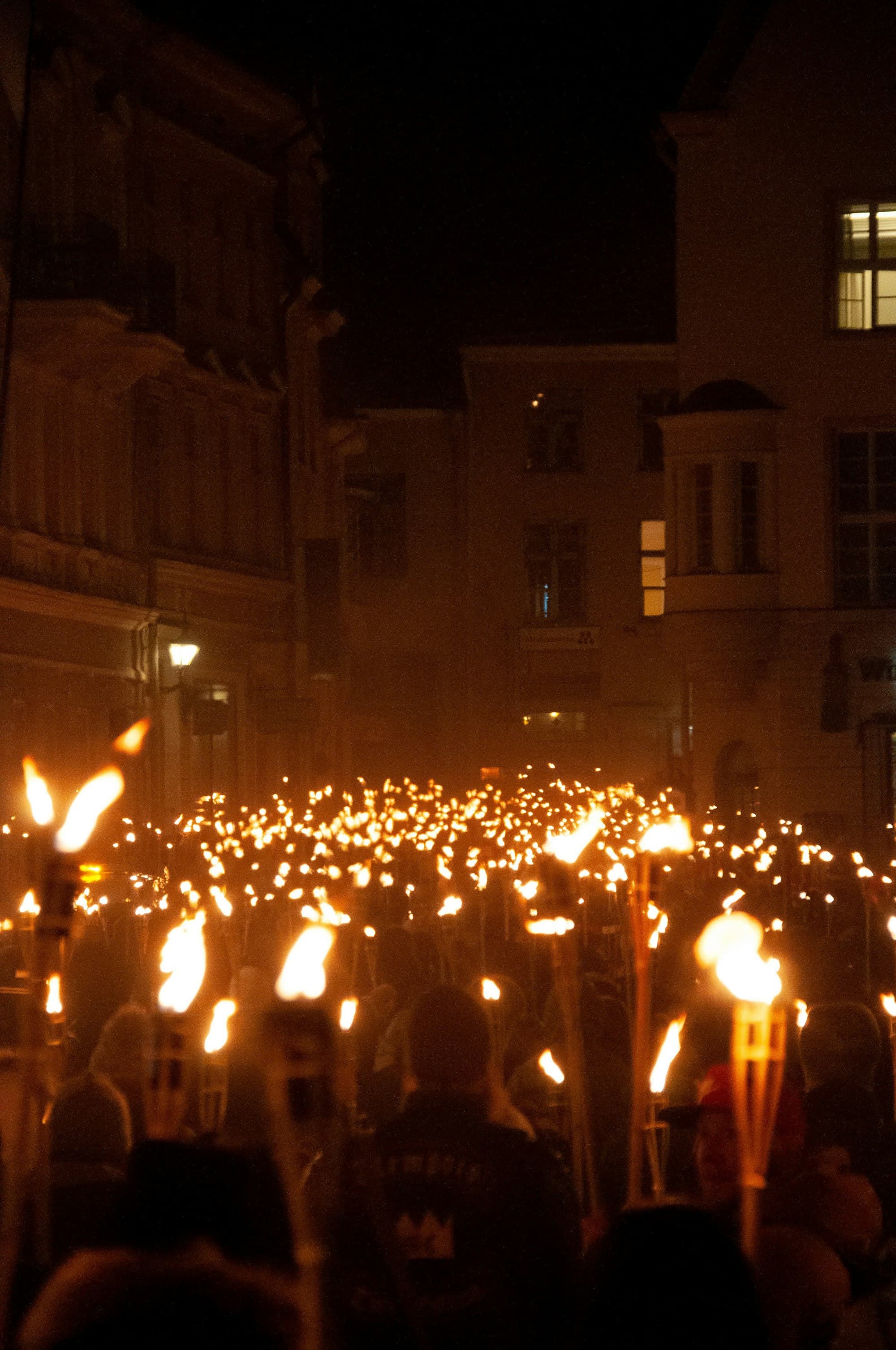 People gathered in front of concrete buildings carrying torches