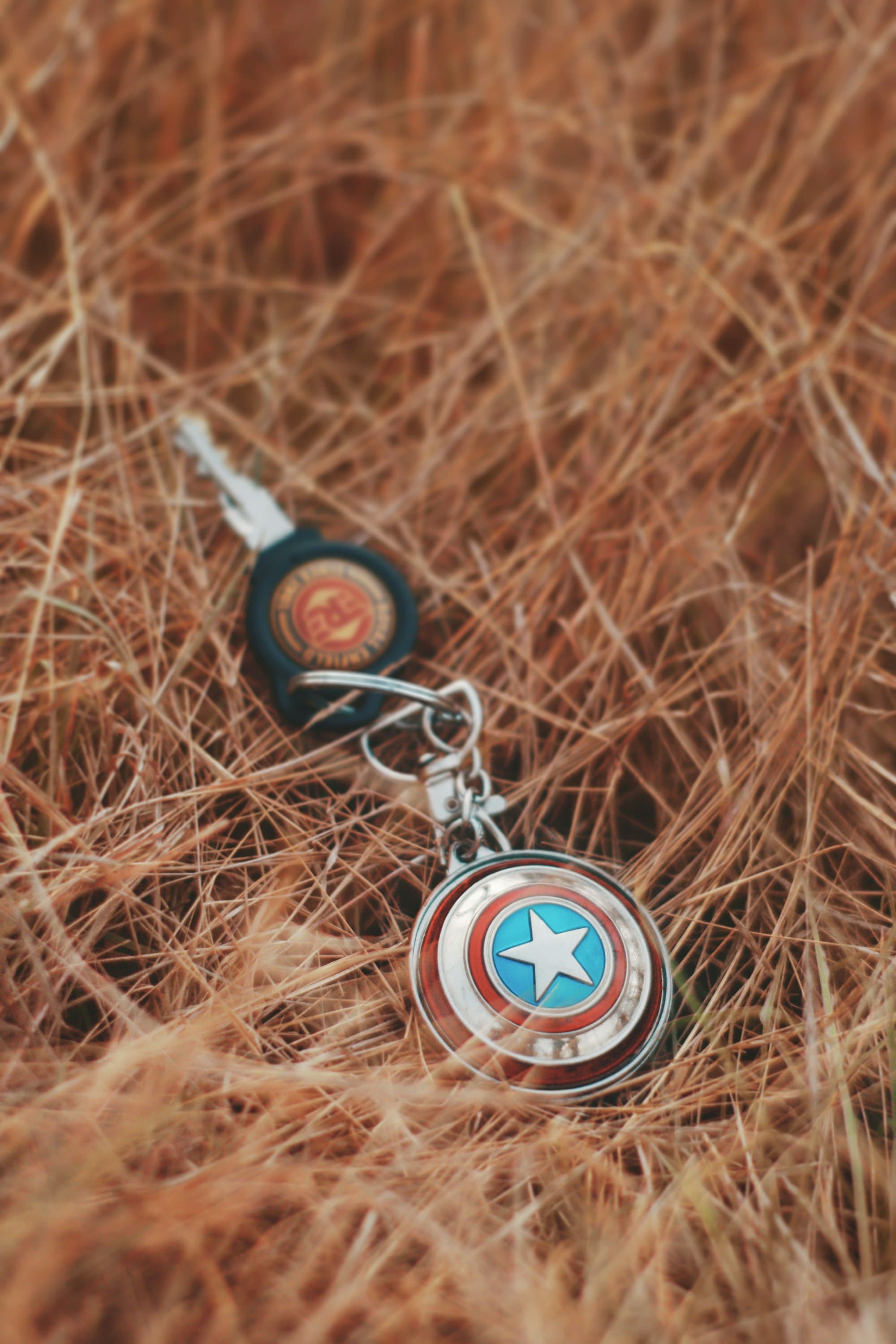 captain america keychain attached to a carkey in a pile of grass