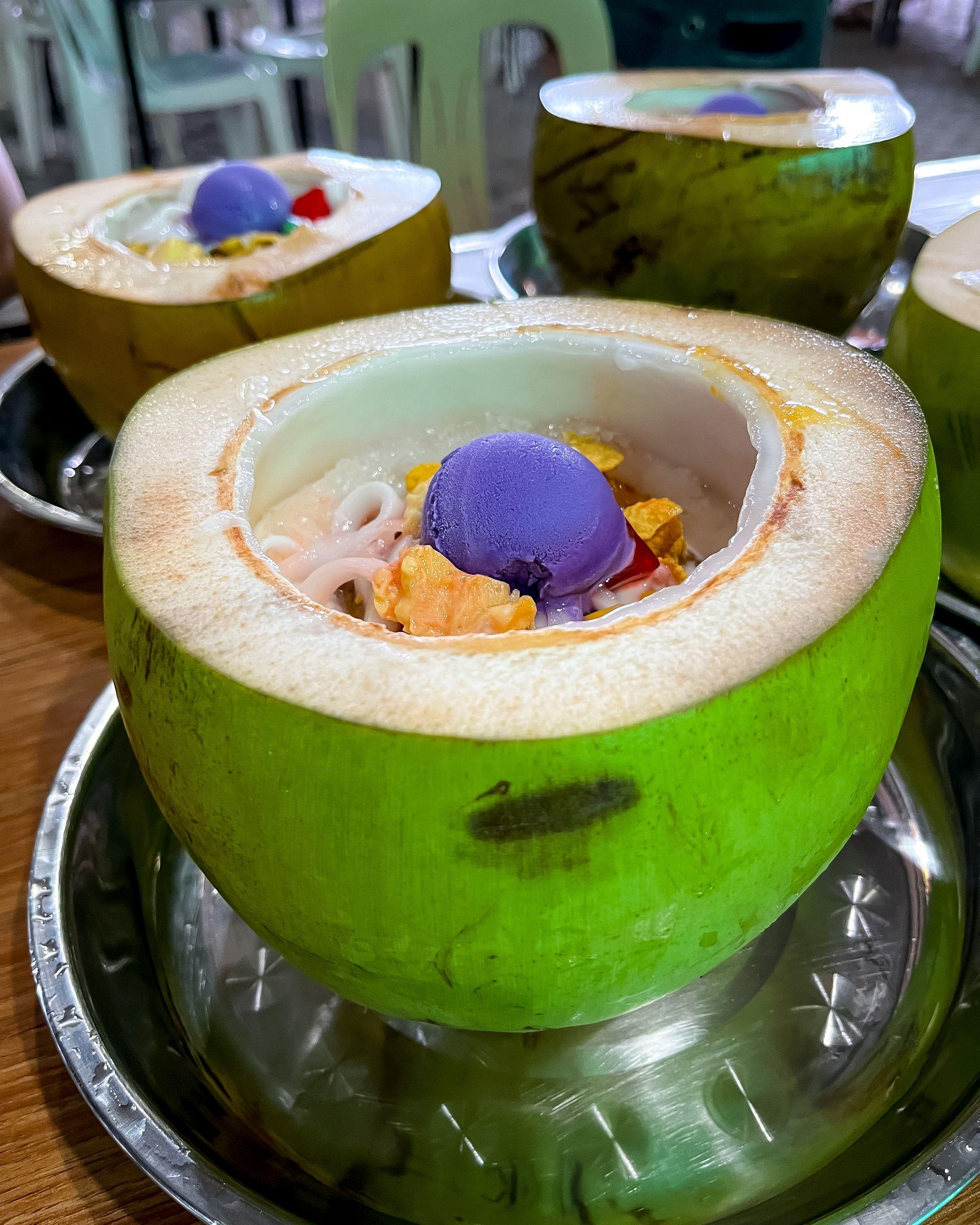 Image of a coconut sliced open and filled with Halo Halo.