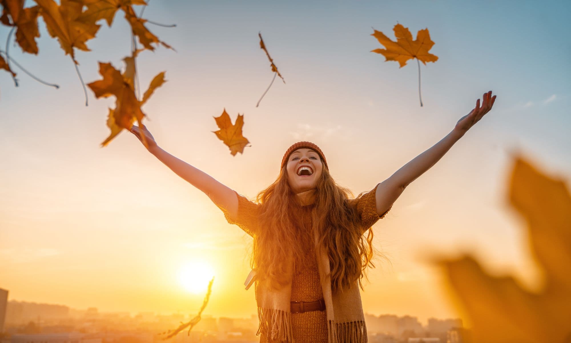 Woman throwing fall leaves in the air.