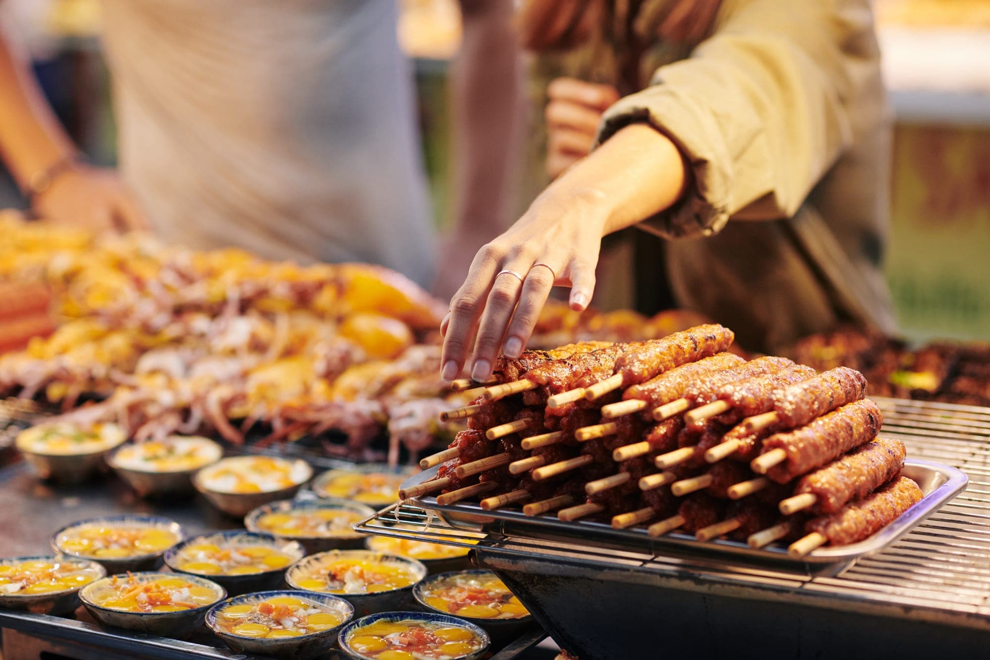 Woman grabbing a meat skewer at a streetfood stall