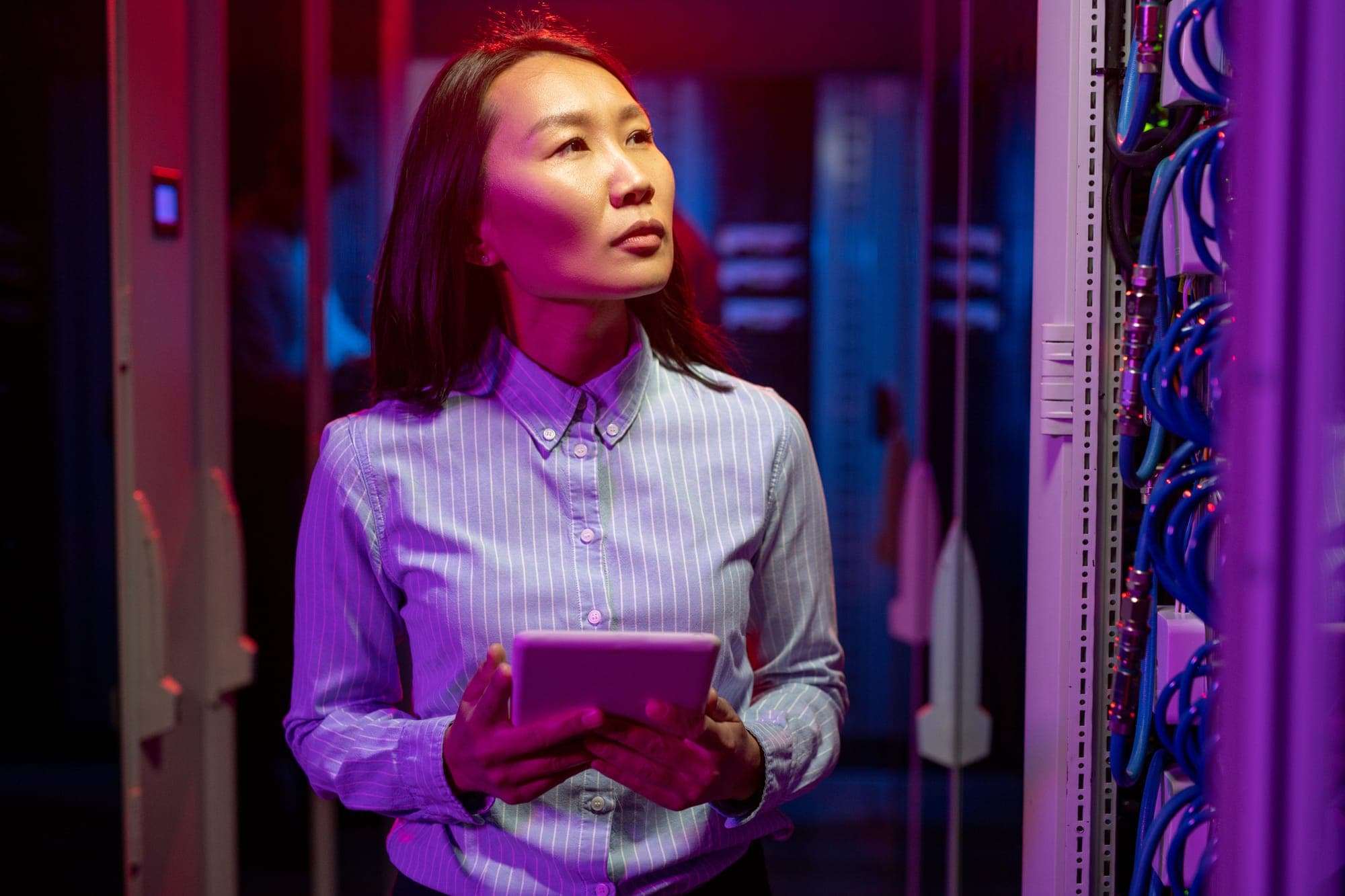 Woman checking on cabling in a server room.