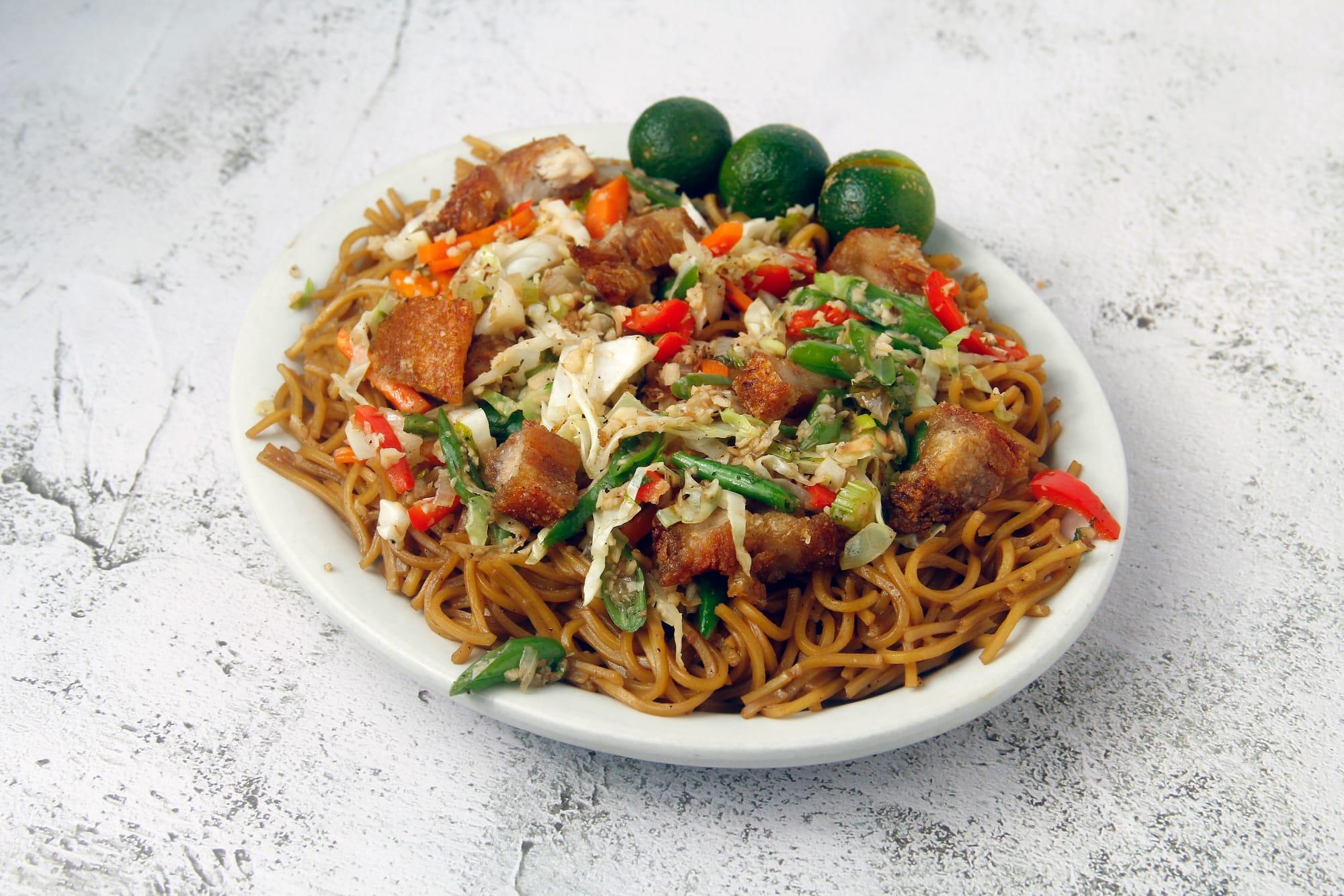 Filipino noodle dish, pancit canton, with meet and calamansi on top