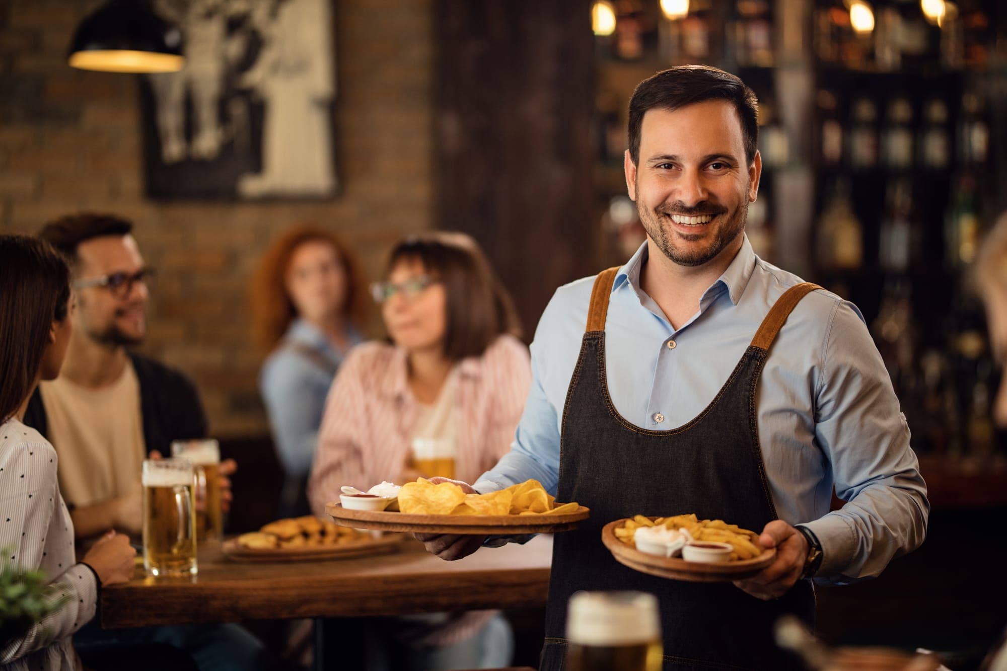 Waiter standing with plates of nachos in hand.