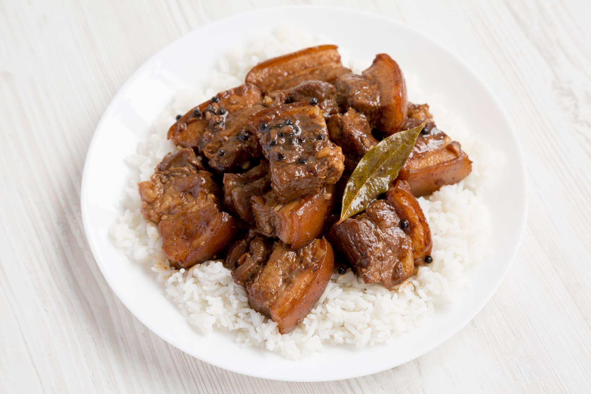 slices of marinated pork belly on a plate of rice
